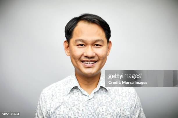 Portrait of mid adult male professional smiling. Confident businessman is wearing shirt. Executive is over white background.