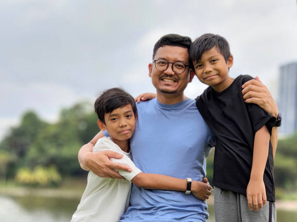 A Muslim man is spending leisure time with his two young sons at public park.